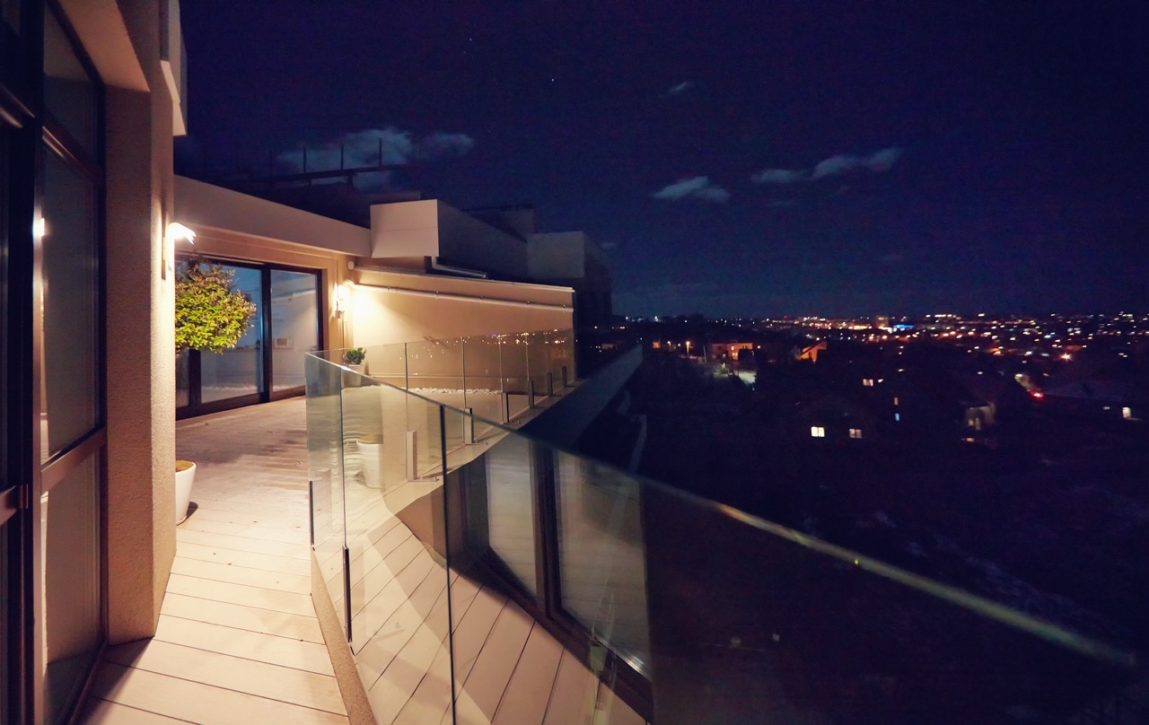 rooftop patio with glass balustrade and city view at night